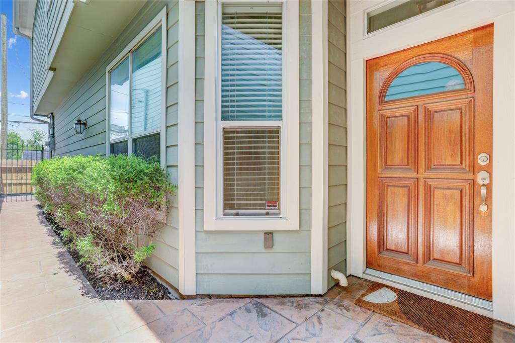 The entryway includes a gated side entrance for added security. Trimmed landscaping lines the walkway leading up to the front door, offering a clean and welcoming path for guests.