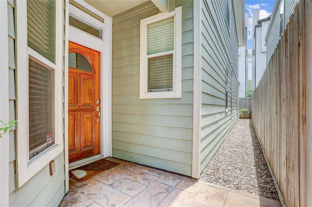 Another view of the entry shows the walkway along the side of the home, leading directly to the patio. The gravel path is low-maintenance and fully enclosed with a privacy fence.