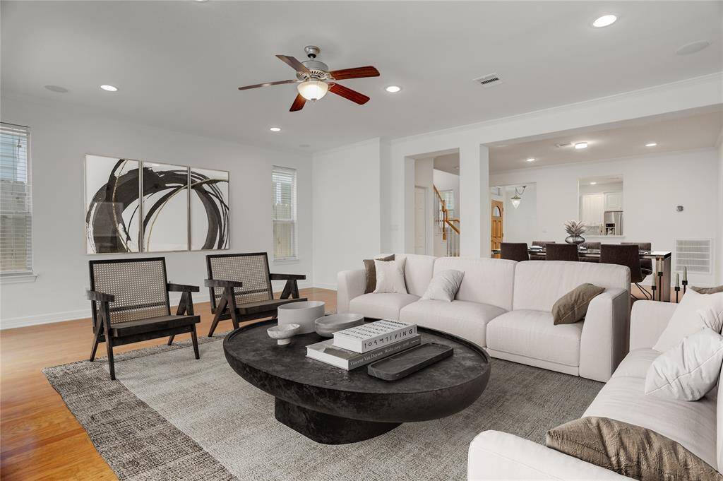 This bright and inviting living area features engineered wood floors and natural light pouring in through multiple windows. Recessed lighting and a ceiling fan add comfort, while the built-in surround sound system elevates your entertainment experience. This photo is virtually staged.