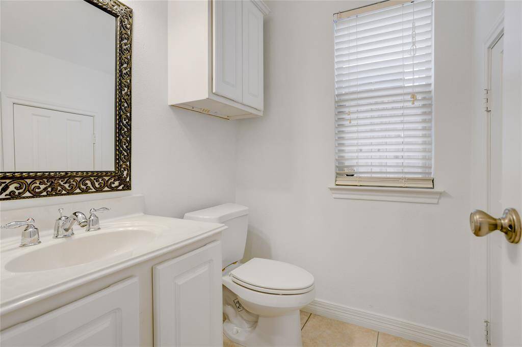 The half bathroom is conveniently located just off the main living area, making it easily accessible for guests. It features a spacious vanity with cabinet storage, a decorative framed mirror, and a window that brings in natural light, making it ideal for guests.