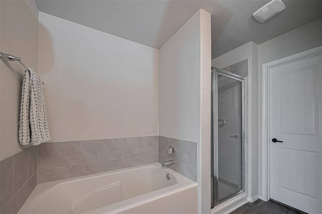 Primary bath includes spacious bathtub, a separate glass-enclosed shower.