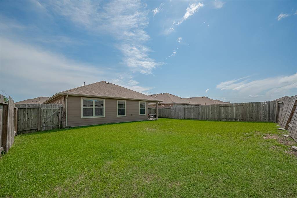 Spacious fenced backyard with a well-maintained lawn and a view of a single-story house, perfect for outdoor activities and privacy.