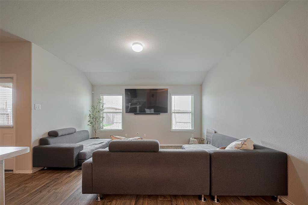 Spacious living room with high ceilings, featuring two windows provide natural light, enhancing the room's airy feel.