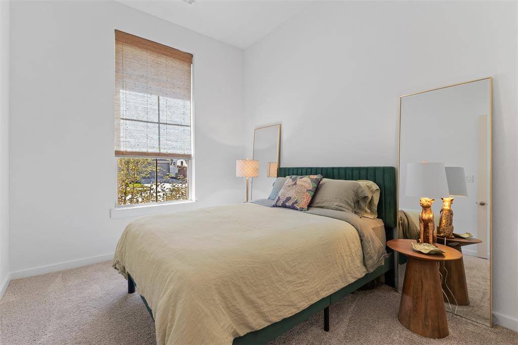 One of the secondary bedrooms that has plush carpet, high ceilings, and a tall window with custom shades.