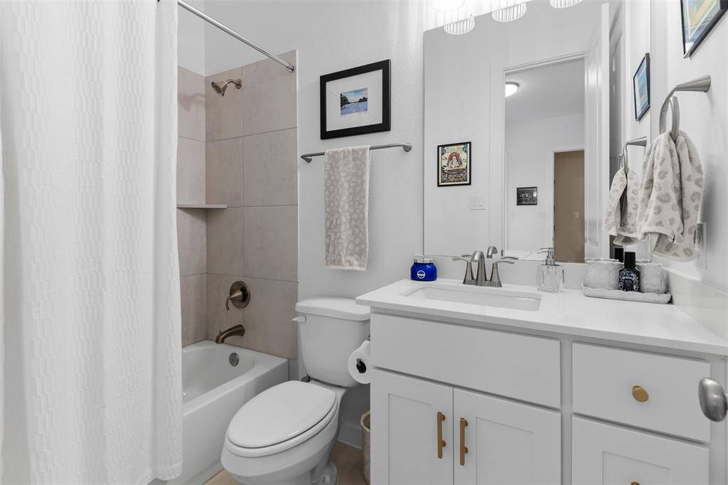 Ensuite secondary bathroom with a shower/tub combo, tile floors, spacious vanity with quartz countertop and lots of storage space.
