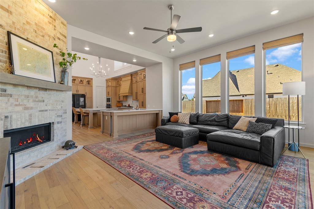 Opposite view of the living room to show off the beautiful fire place and the openness to the kitchen and dining area. It also has custom shades in the tall windows.