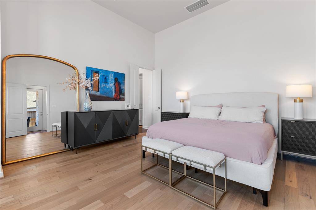 Very large primary bedroom featuring engineered hardwood floor and high ceilings.