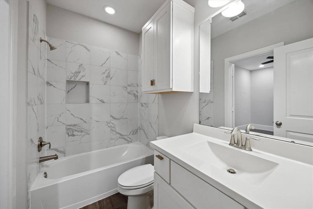 The first-floor bathroom includes a tub/shower combo with a built-in shampoo niche—offering both function and a clean, modern touch.