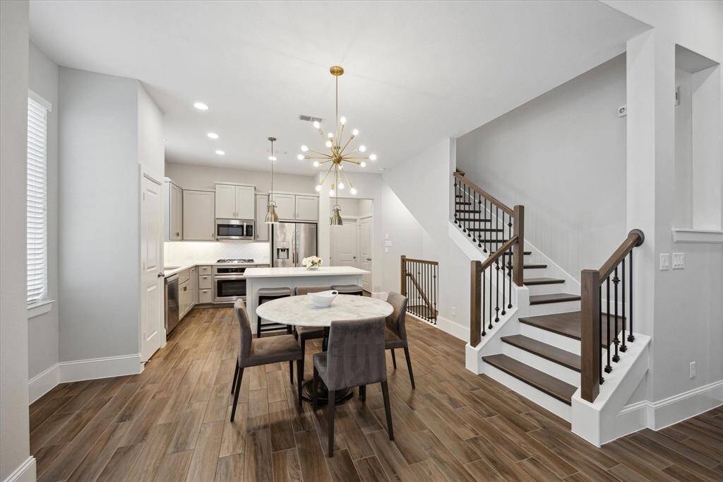 Bright and airy living room with tall ceilings, rich engineered wood floors, and an open layout that flows seamlessly into the dining area and kitchen. Filled with natural light—perfect for everyday living and entertaining.