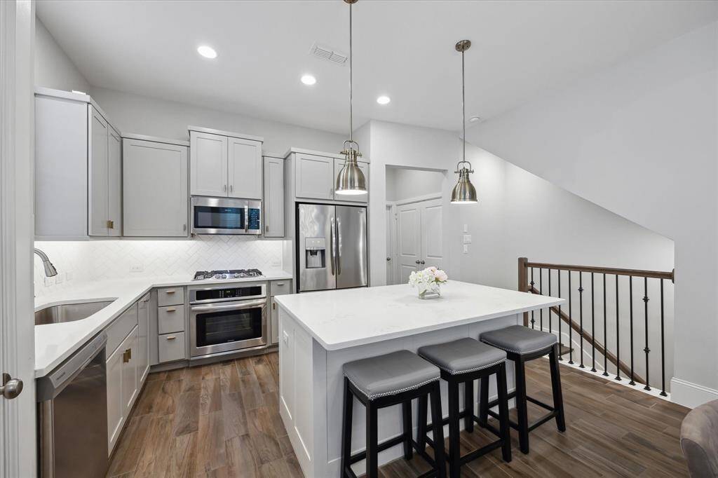 A large single-basin sink, sleek gas cooktop, and eye-catching designer lighting elevate this kitchen into a space that’s as functional as it is beautiful—perfect for home chefs and stylish entertainers alike.