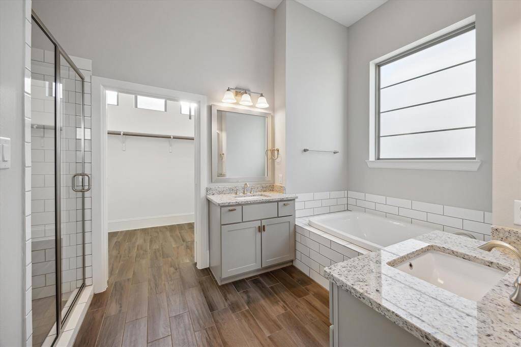 The luxurious en suite bathroom offers dual sinks, a large soaking tub perfect for relaxing evenings, and a walk-in shower for a spa-like experience—thoughtfully designed for both comfort and style.