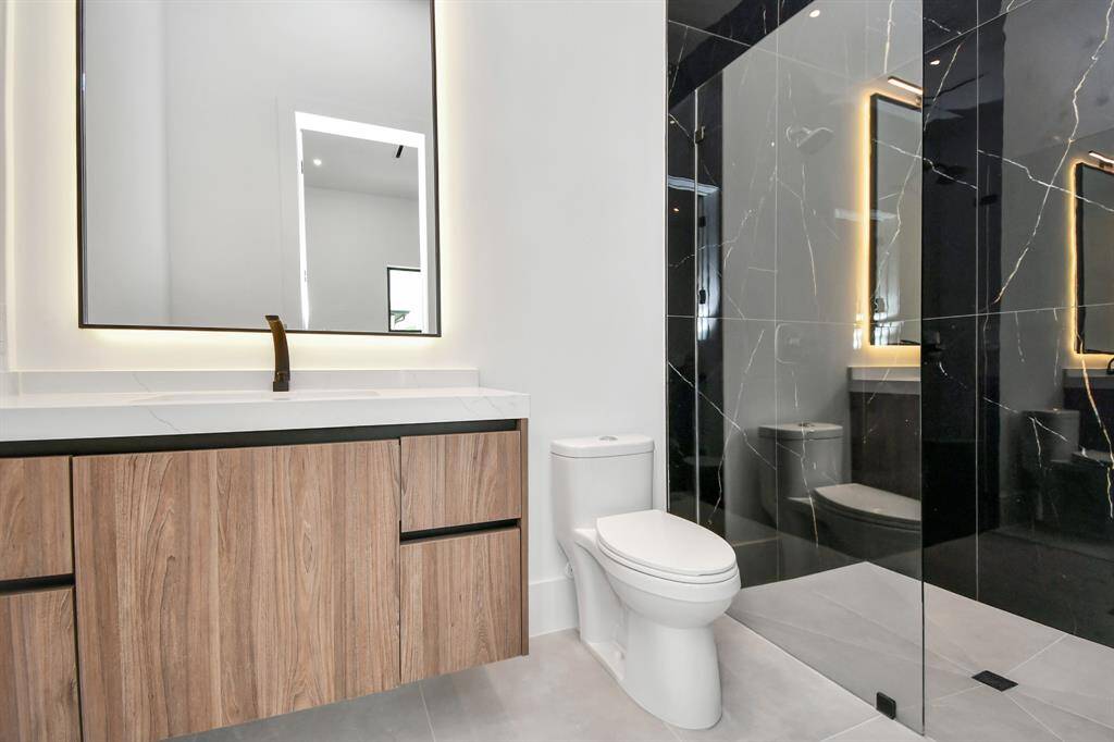 Step into luxury with this stunning bathroom featuring a spacious walk-in shower, modern hardware, and sleek tile extending from floor to ceiling.