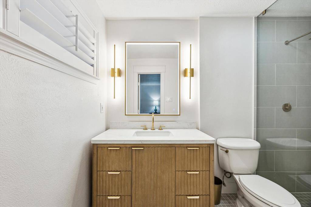 Reeded Oak Master Bath vanity w/ quartz countertop & soft close hinges. LED Master Bath mirror and brass wall sconces with  Moroccan unlacquered brass plumbing fixtures.