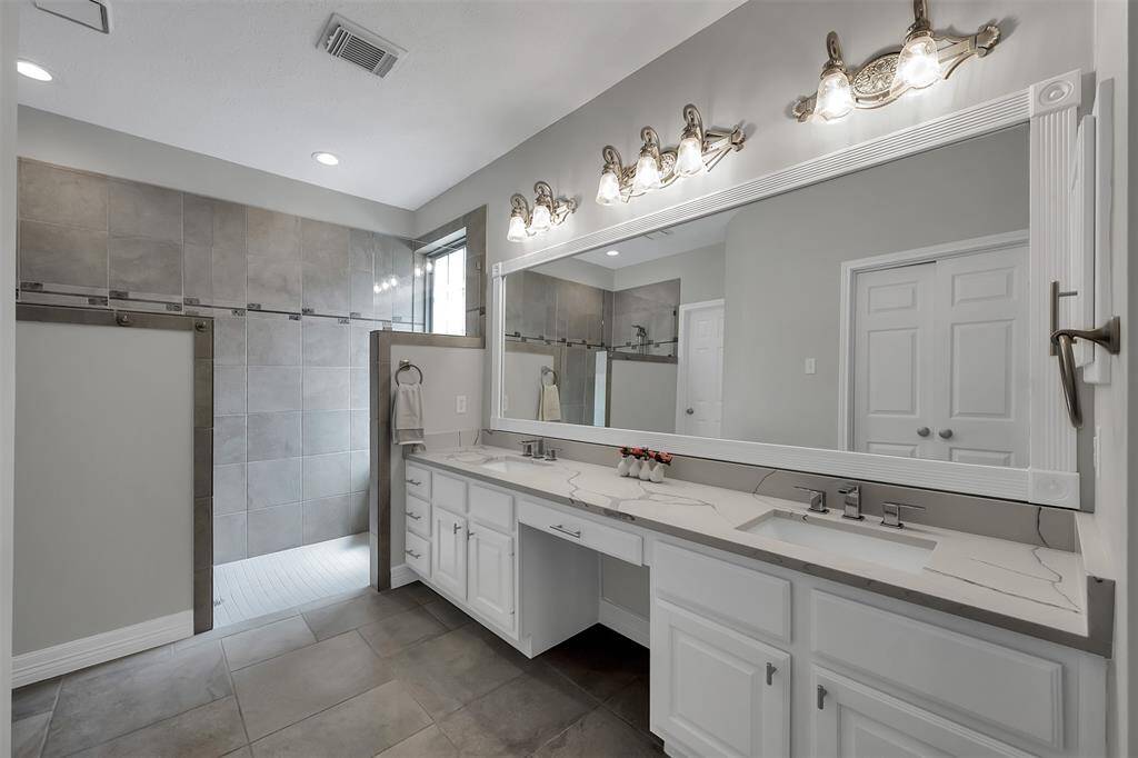 View of roll in shower w/ 2 sitting areas, adjustable shower head &recessed cubbies.