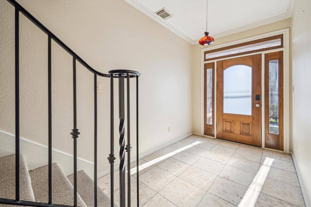 Another look at the spacious entry featuring the solid wood door with sidelights, transom, travertine flooring and decorative chandelier.