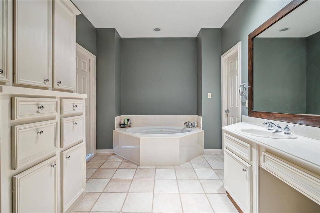 Primary Bath – 12 x 9:  Another view of the primary bath showing soaking tub.  Walk-in closet on the right and access to the primary bedroom on the left via 6-panel doors.
