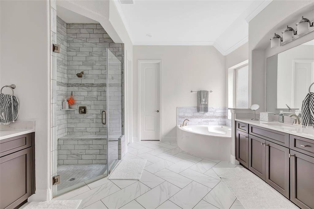 Well lit primary bath featuring soaking tub and large walk in shower