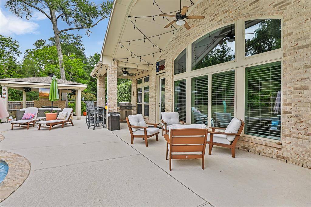 This photo showcases a spacious backyard with a covered patio, outdoor seating area, and an above-ground pool. The lush lawn and landscaped garden beds provide a serene, inviting atmosphere, ideal for relaxation and entertaining.