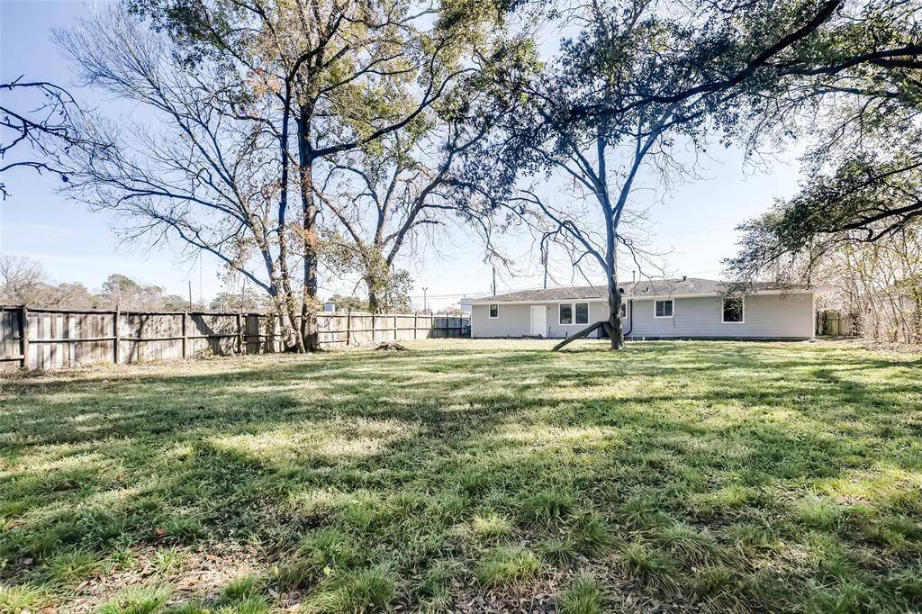 Expansive backyard with large trees.