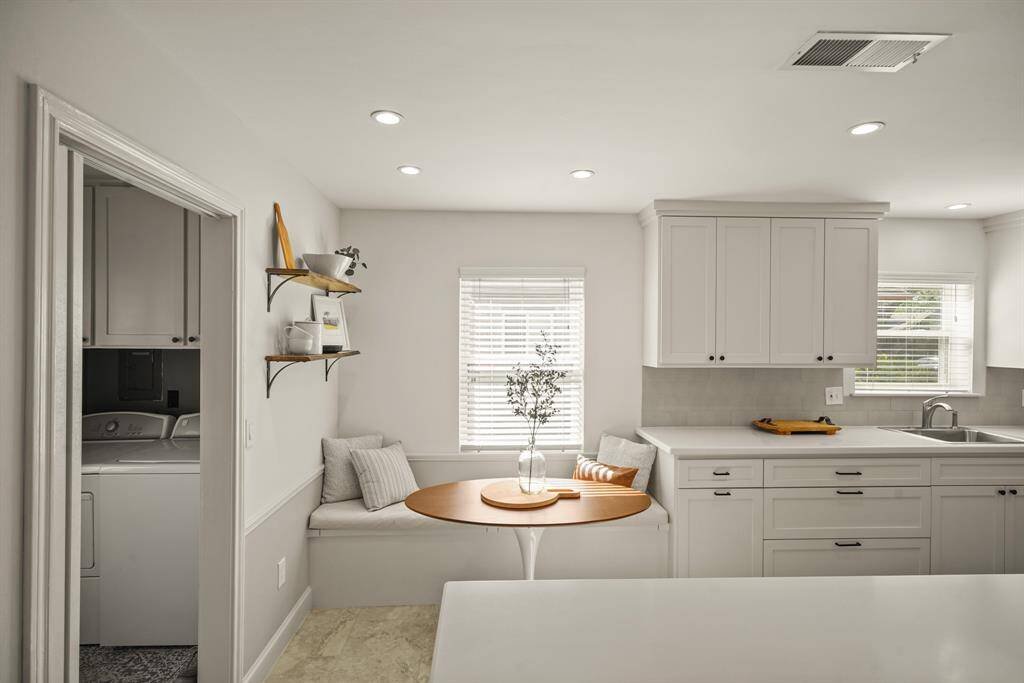 Light and bright kitchen with quartz counters, built in banquette, and lots of cabinets and drawers.