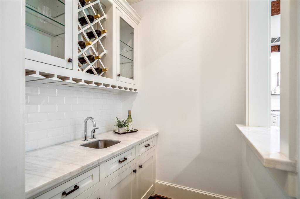 Thoughtfully tucked just off the main living space, the wet bar boasts marble countertops, custom glass cabinetry, and dedicated wine storage - an elegant touch for effortless entertaining.