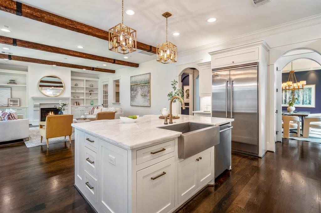 Anchored by a stainless steel farmhouse sink and topped with honed marble, the oversized kitchen island serves as a natural gathering place for everything from after-school snacks to holiday hosting.