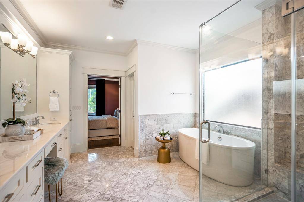 The primary bathroom is a true retreat, wrapped in luxurious marble with an expansive double vanity, spa-style shower, large soaking tub, and an overall inviting place to unwind.