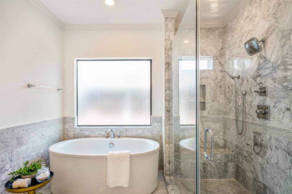 Bask in the luxury of a deep soaking tub framed by marble wainscoting, or enjoy the show-stopping glass shower, clad in dramatic veined marble and outfitted with multiple sprays for an all around, true spa experience.