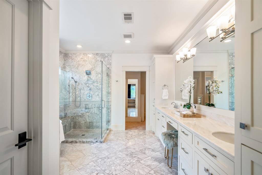 An elegant dual vanity with a dedicated makeup area and extensive cabinetry completes this refined primary bath, offering both beauty and practicality in equal measure.