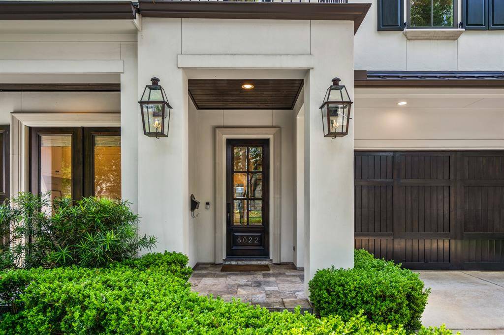 The entry sets the tone with elegant gas lanterns, a covered stone front porch, and a glass-panel front door that balances privacy with a warm welcome.