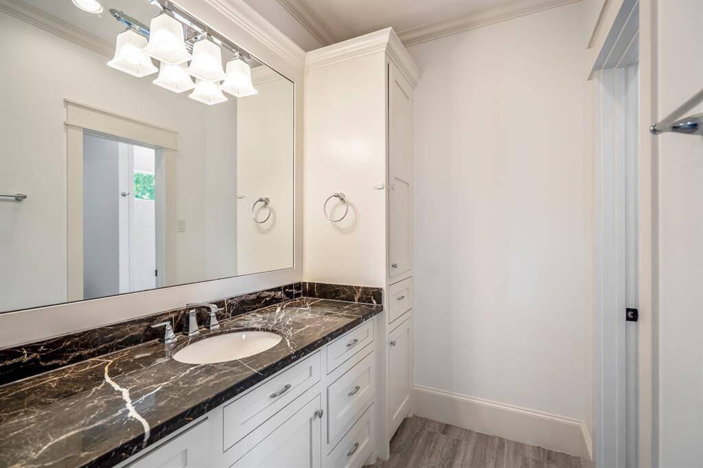 Dramatic veining and a bold hue give the marble vanity top in this full bath a luxe presence, complemented by ample storage and sleek fixtures.