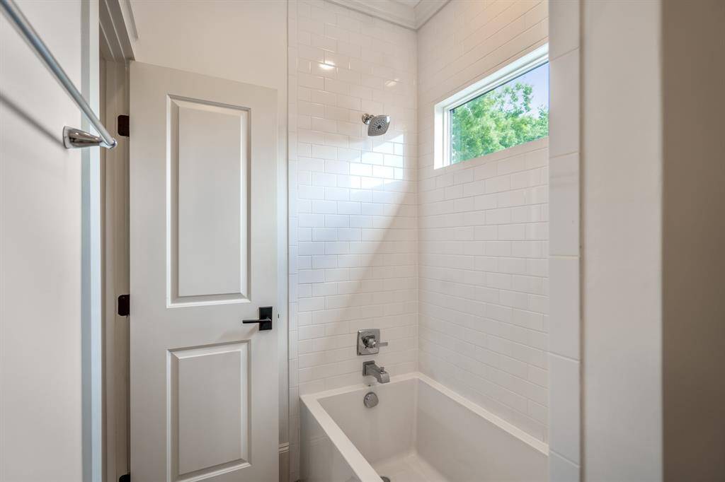 Jack & Jill bathroom with classic white subway tile surrounds the tub-shower combo, where a high window draws in natural light while maintaining privacy, perfect for a tranquil soak or a kid-friendly splash-time!