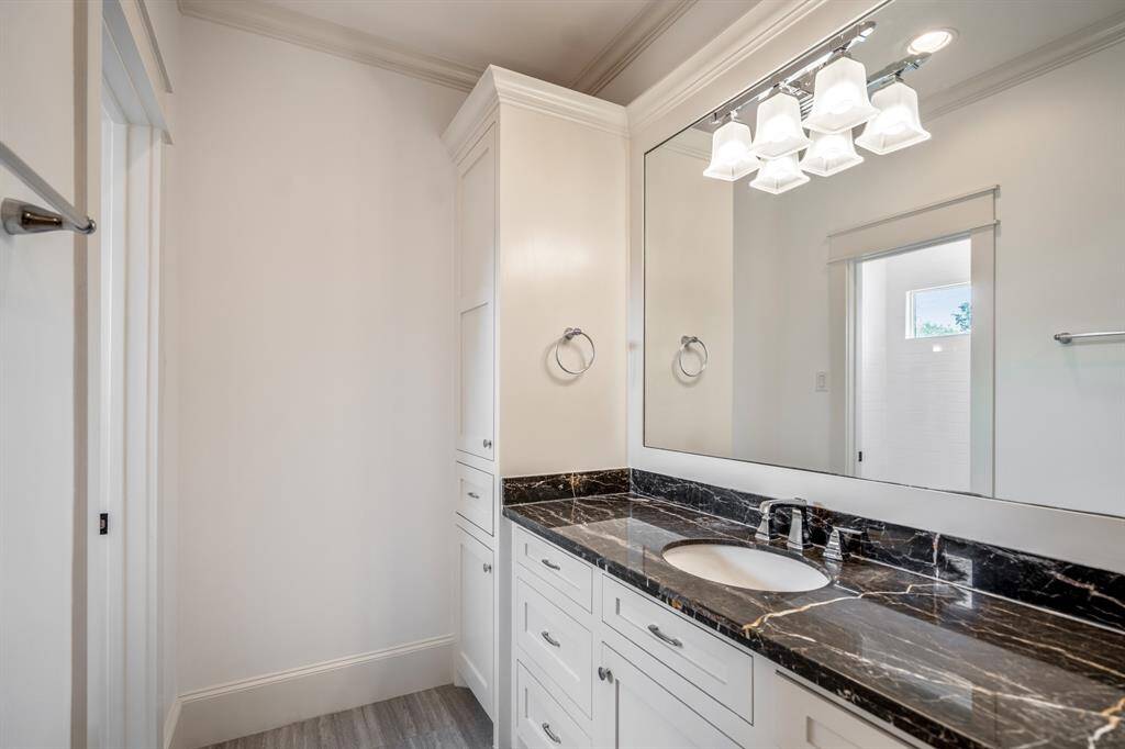 This secondary bath impresses with statement black marble countertops, clean white cabinetry, and sleek chrome fixtures that bring a touch of luxury to the everyday routine.