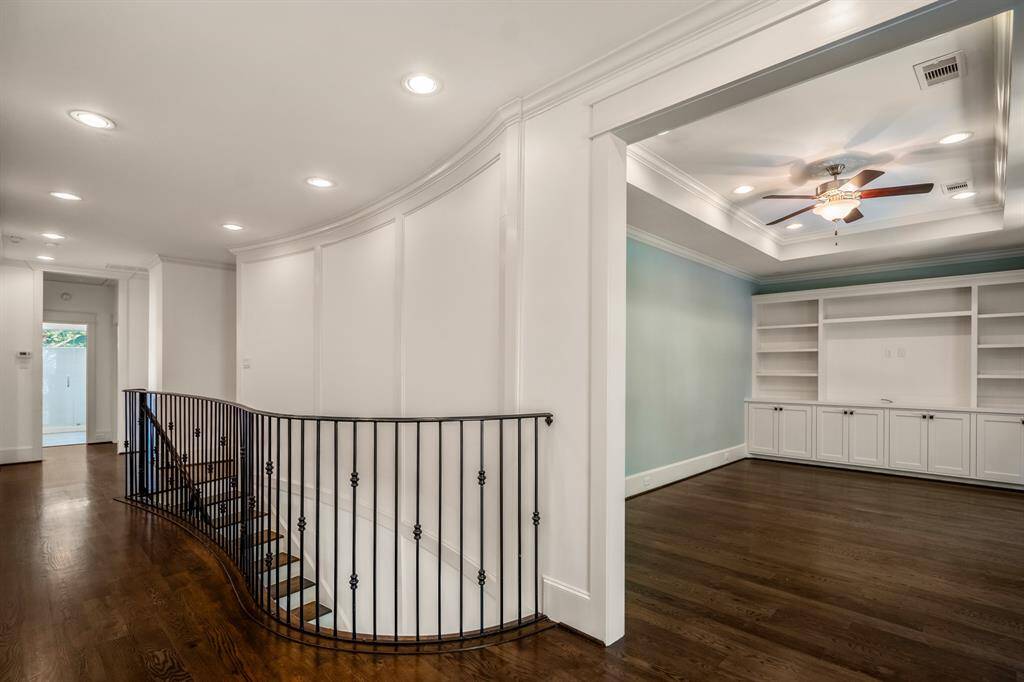 The upstairs hallway makes a dramatic impression with its softly curved architecture and elegant wrought iron railing, connecting the upstairs bedrooms with the game room & balcony in classic style.