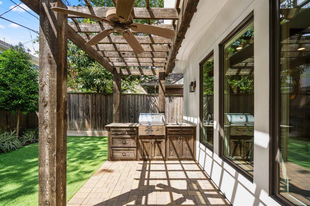 A summer kitchen under a rustic pergola sets the scene for memorable cookouts and family meals al fresco, complete with a built-in gas grill, sink and prep space.