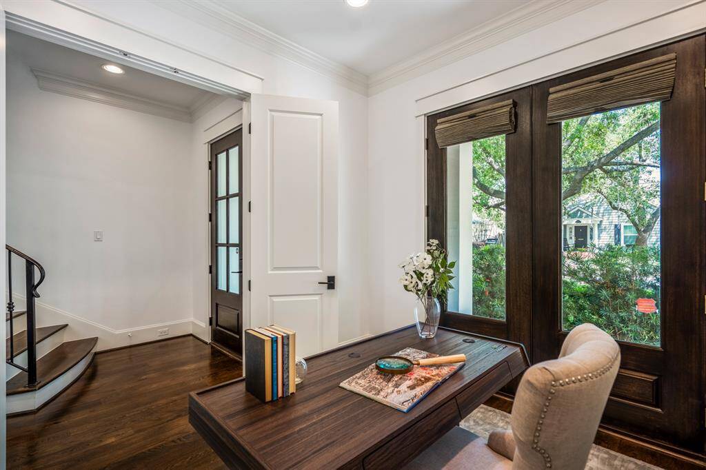 A dedicated home office sits just off the front entry, designed for focus and flexibility with wide-plank white oak wood floors and tree-filtered light from the oversized faux double door windows.