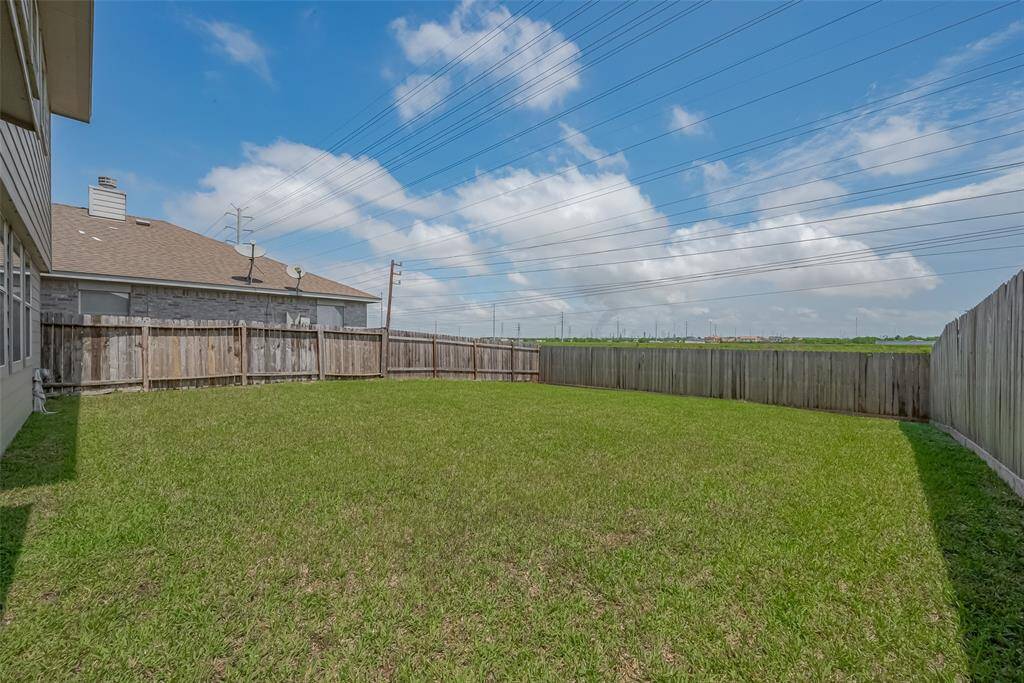 Spacious backyard with well-maintained grass, enclosed by a wooden fence, providing privacy and ample space for outdoor activities.