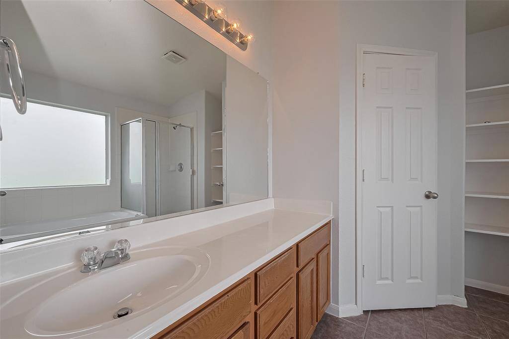 This bathroom features a spacious vanity with ample storage, a large mirror, a separate shower, a bathtub, and built-in shelving for convenience.