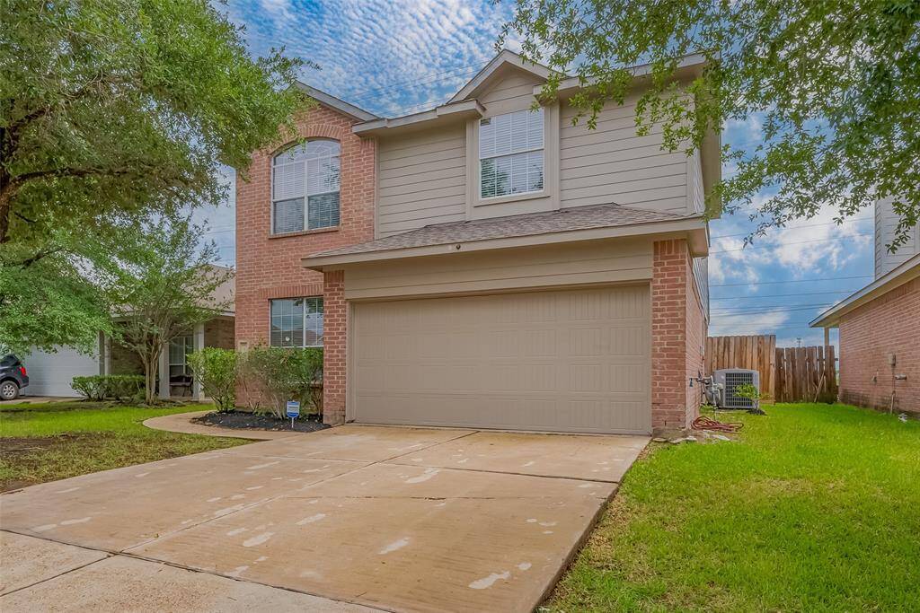 This is a two-story brick and siding home with a two-car garage. It features a well-maintained lawn and mature trees, offering a welcoming curb appeal.