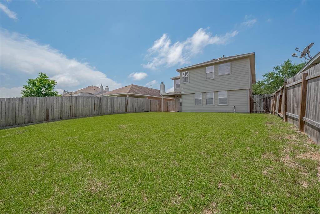 Spacious backyard with a well-maintained lawn, surrounded by a wooden fence for privacy, perfect for outdoor activities and gatherings.