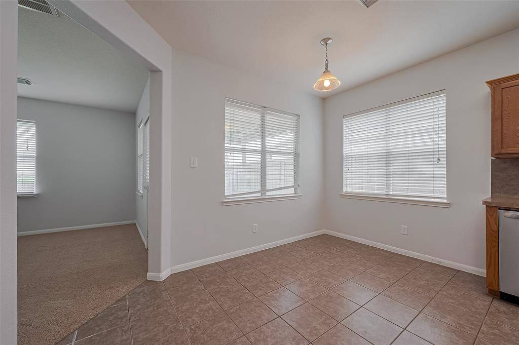 Breakfast nook with large windows and tiled flooring. It connects to living room, enhancing the open layout.