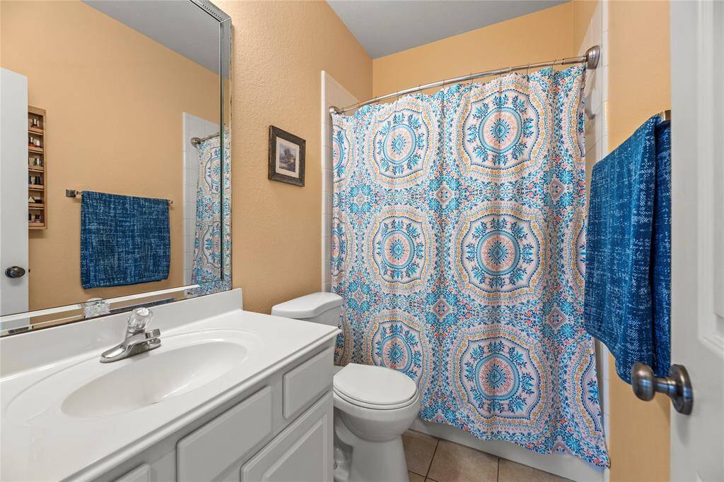 Second bathroom featuring a walk-in shower, toilet, and a vanity with ample storage and a sleek sink.