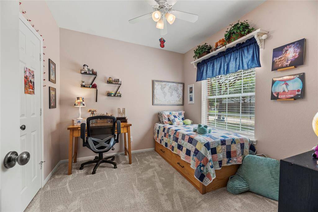 Third bedroom featuring carpet flooring, ceiling fan, and large window.