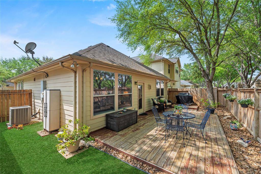 Backyard with a wooden deck, surrounded by mature trees and a wooden fence for privacy. Perfect for outdoor entertaining and relaxation.