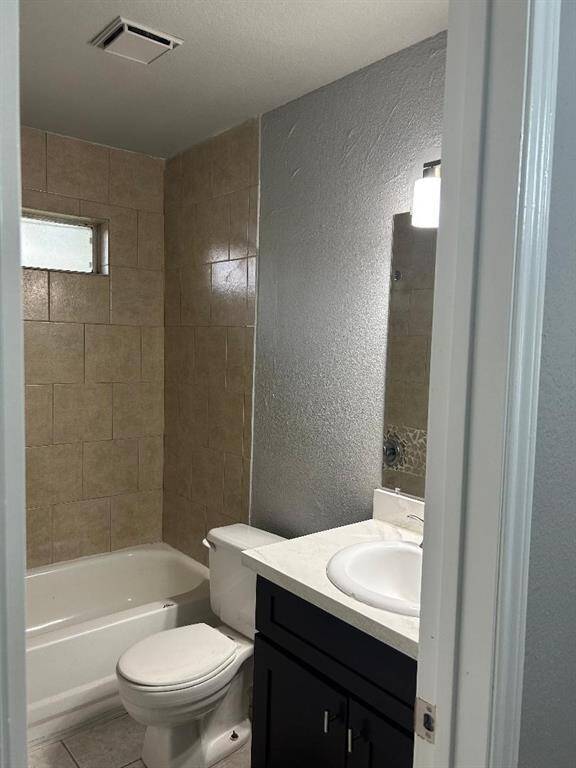 Hall bathroom featuring a bathtub with beige tile surround, and a new dark wood vanity. The space is well-lit by a wall-mounted light above the mirror.