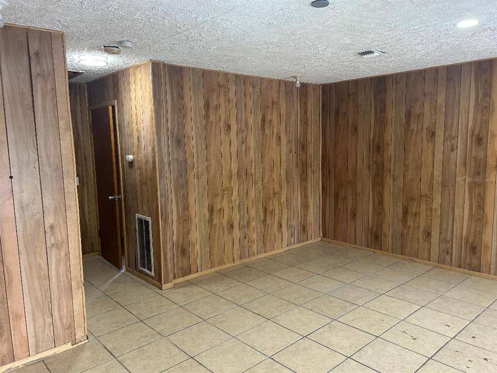 Another view of the large front bedroom with wood paneling and recessed lighting and the door leading to study/office.