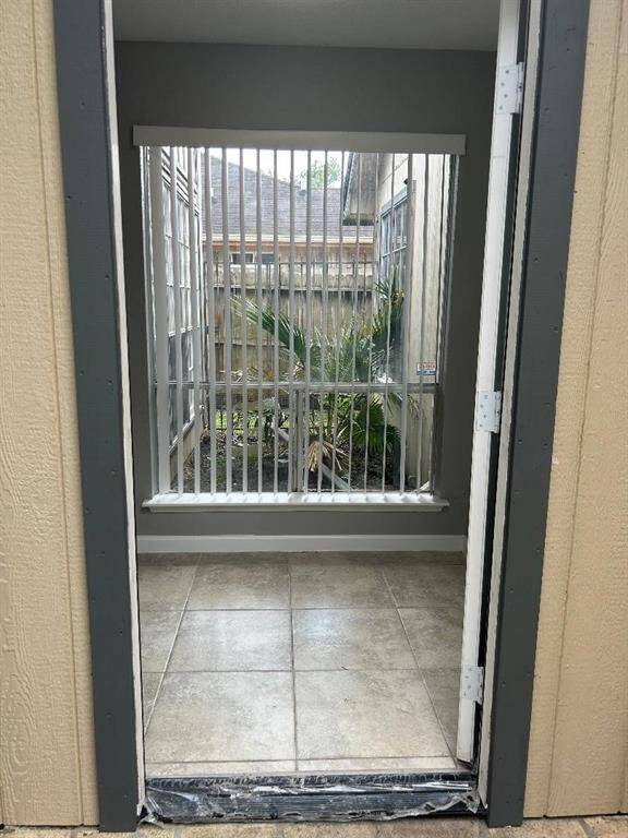 Tiled entryway with vertical blinds on a window overlooking an Atrium. Area provides natural light and a view of the outdoors.