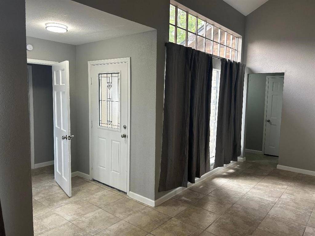 This view is from Formal Dining area that showcases a bright entryway with a decorative glass front door, high ceilings, and large windows.