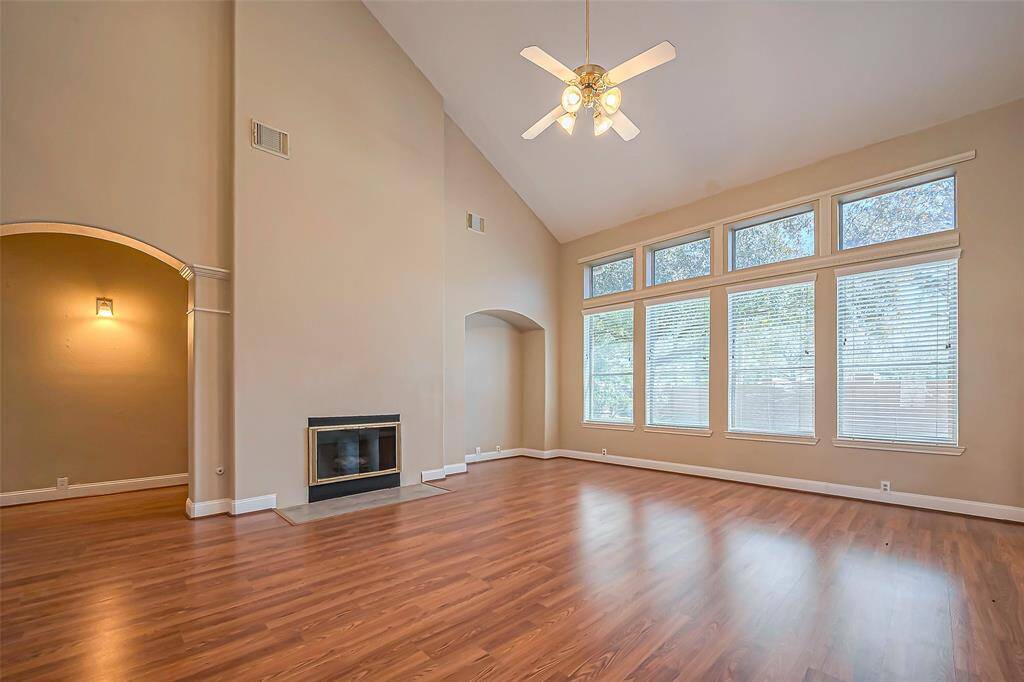 Family room with high ceilings, cozy wood burning fireplace and wall of windows providing plenty of natural light.