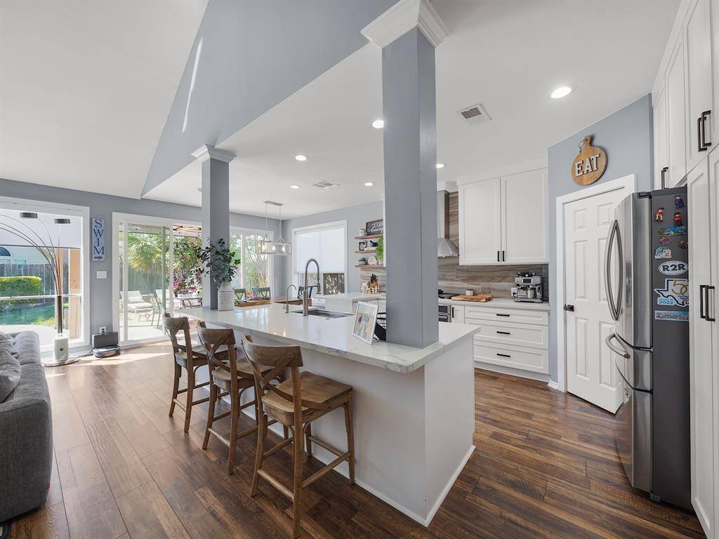 The meticulously updated kitchen boasts quartz countertops that perfectly complement the elegant white cabinets, stainless steel appliances, and stylish tile backsplash.